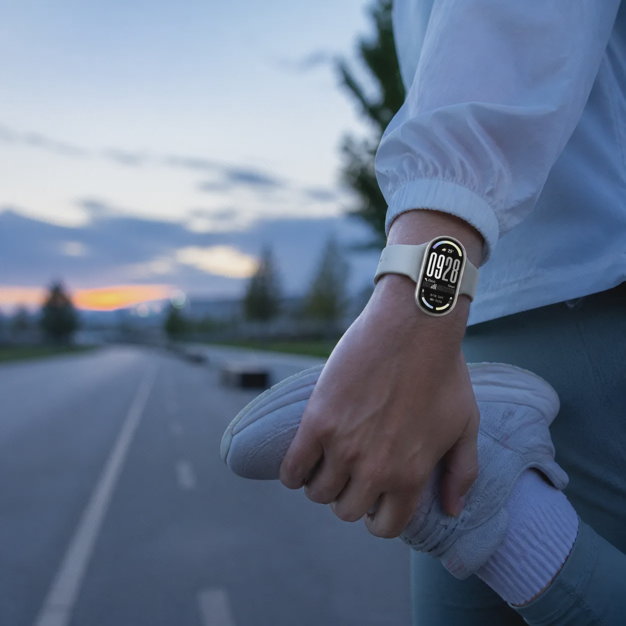 مچ بند Xiaomi Smart Band 10 سفید روی مچ ورزشکار هنگام کشش صبحگاهی در مسیر دویدن