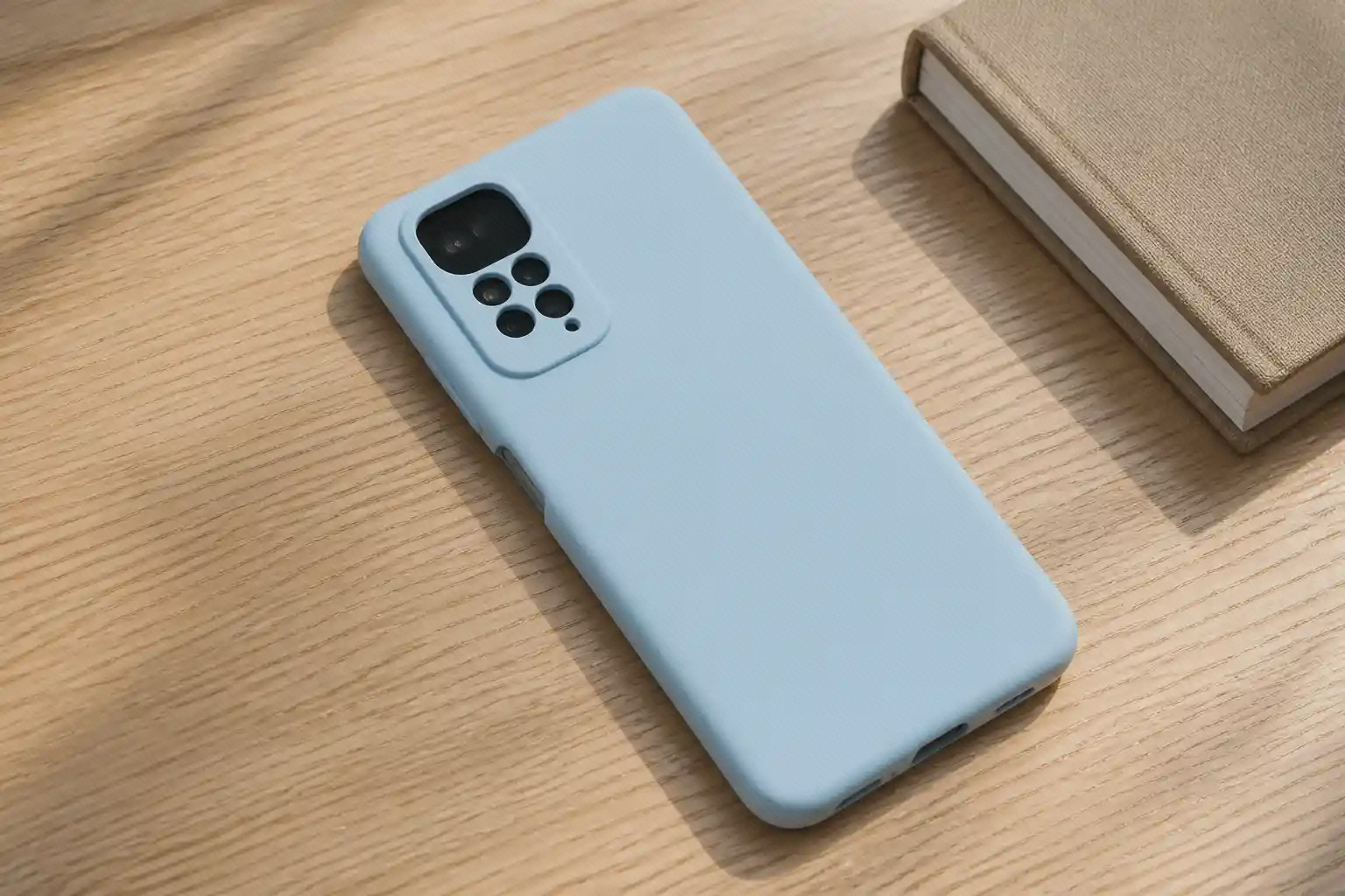 کاور سیلیکونی آبی روشن نصب‌شده روی Redmi Note 12S روی میز چوبی