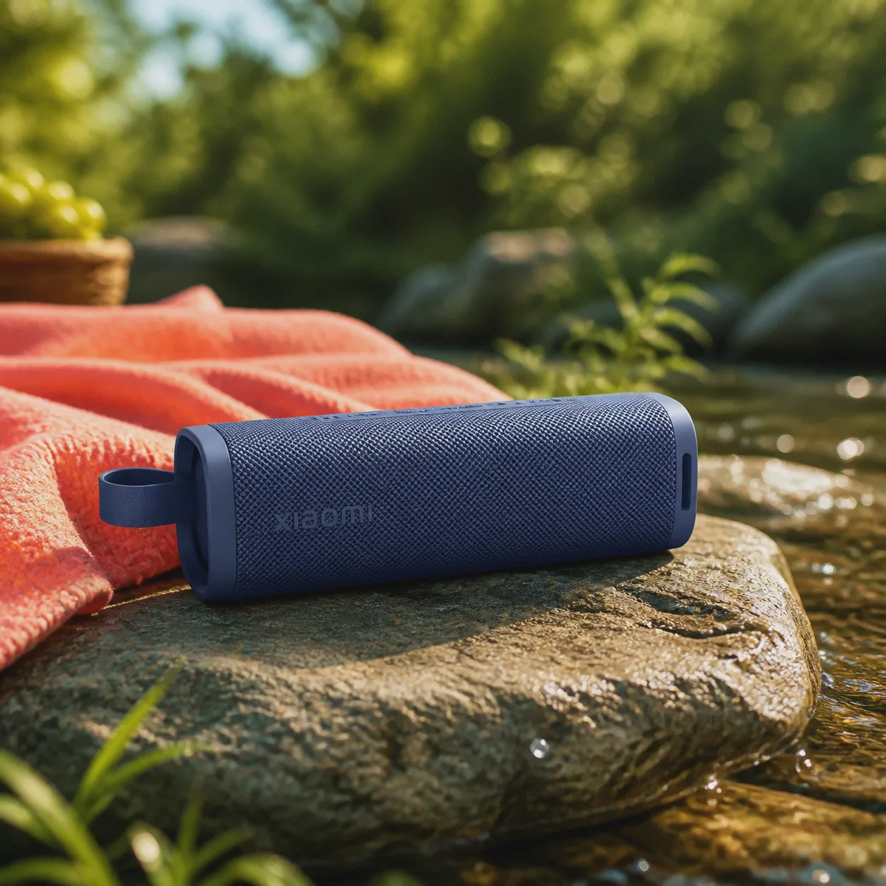 اسپیکر شیائومی Sound Outdoor در فضای باز اسپیکر آبی Xiaomi Sound Outdoor روی سنگ کنار جوی آب و زیر نور تابستانی