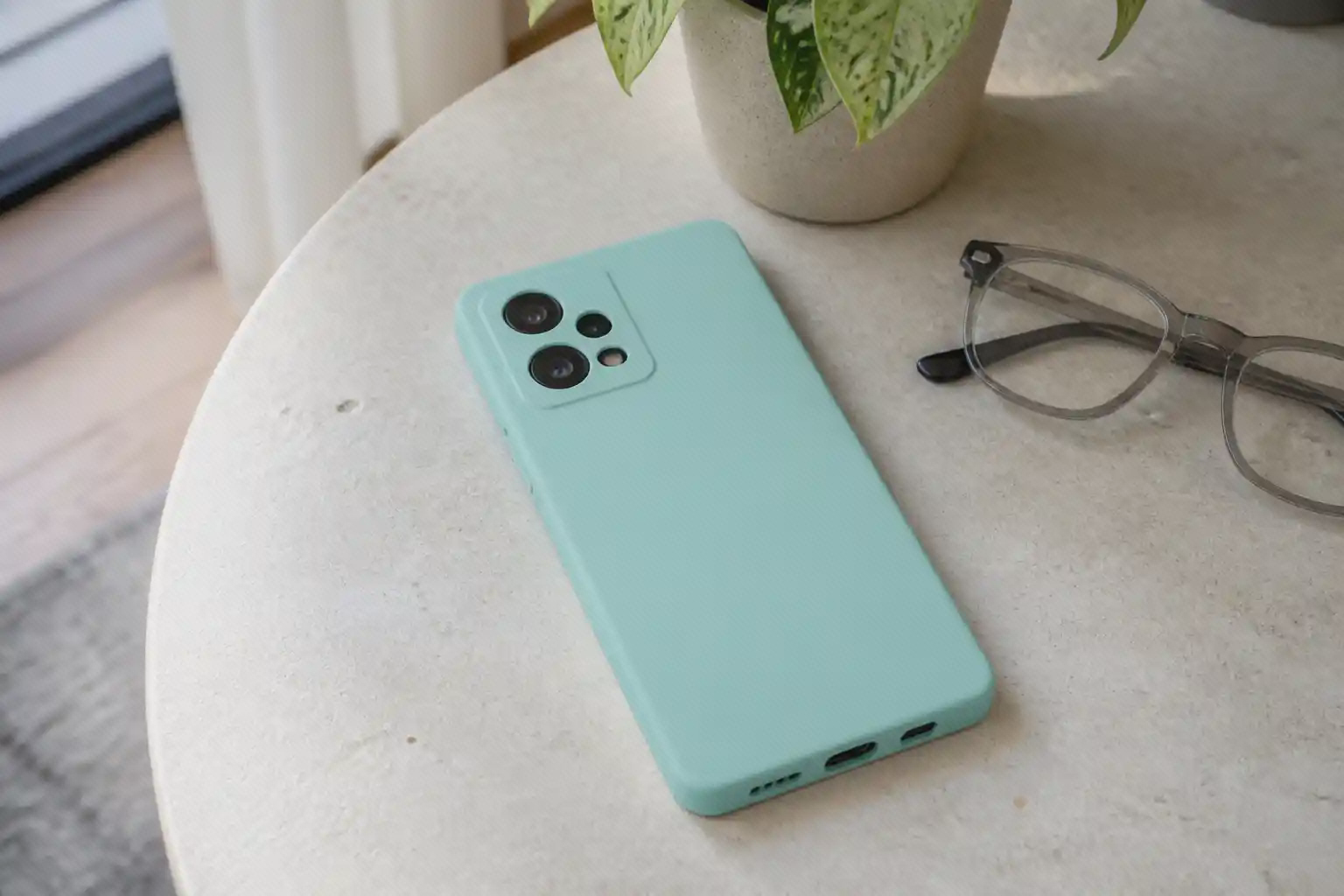کاور سیلیکونی سبز روشن نصب‌شده روی Redmi Note 12 Pro Plus کنار عینک