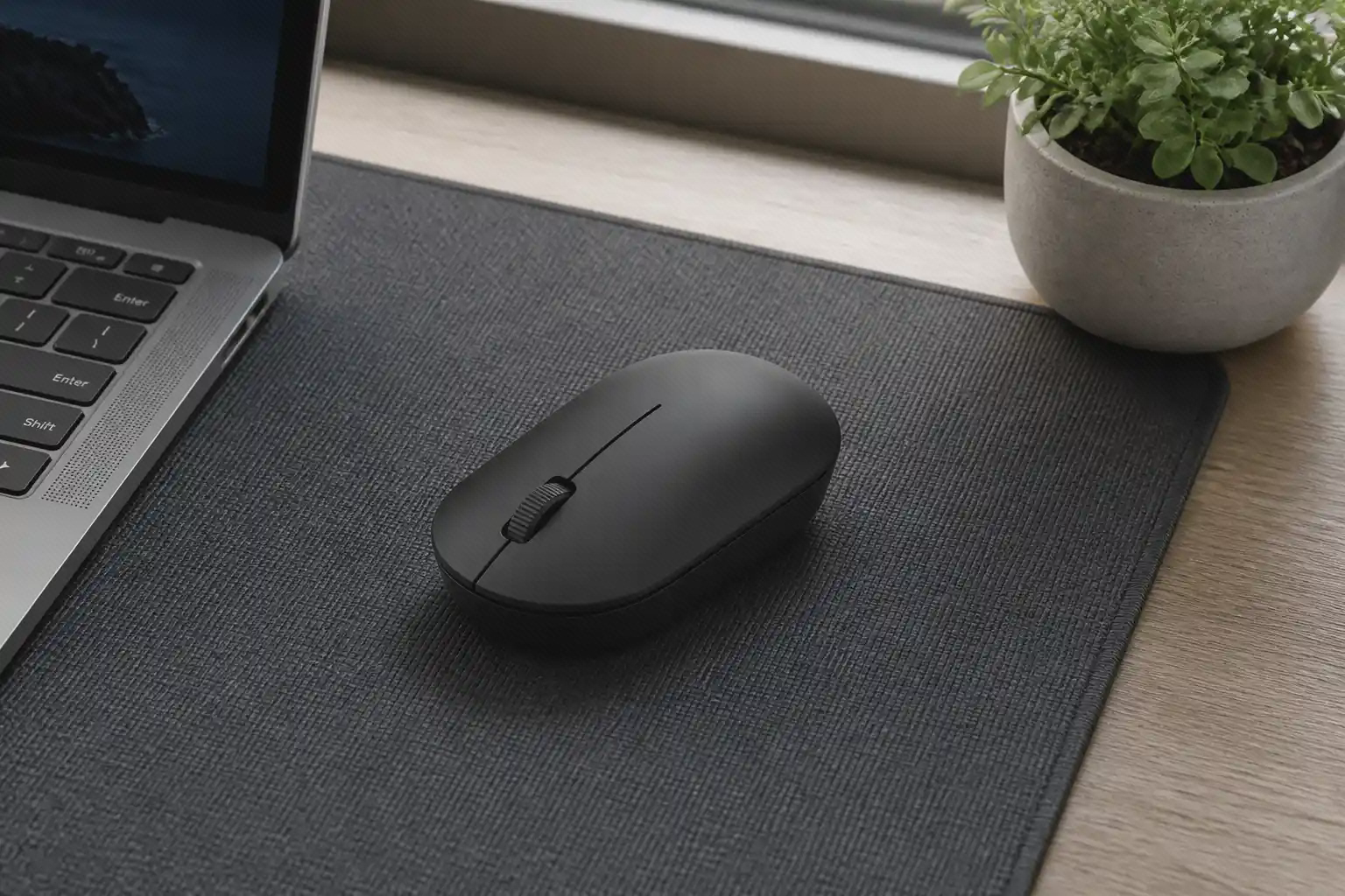 موس مشکی Xiaomi Wireless Mouse Lite 2 با یک چرخ اسکرول روی میز کار کنار لپ‌تاپ