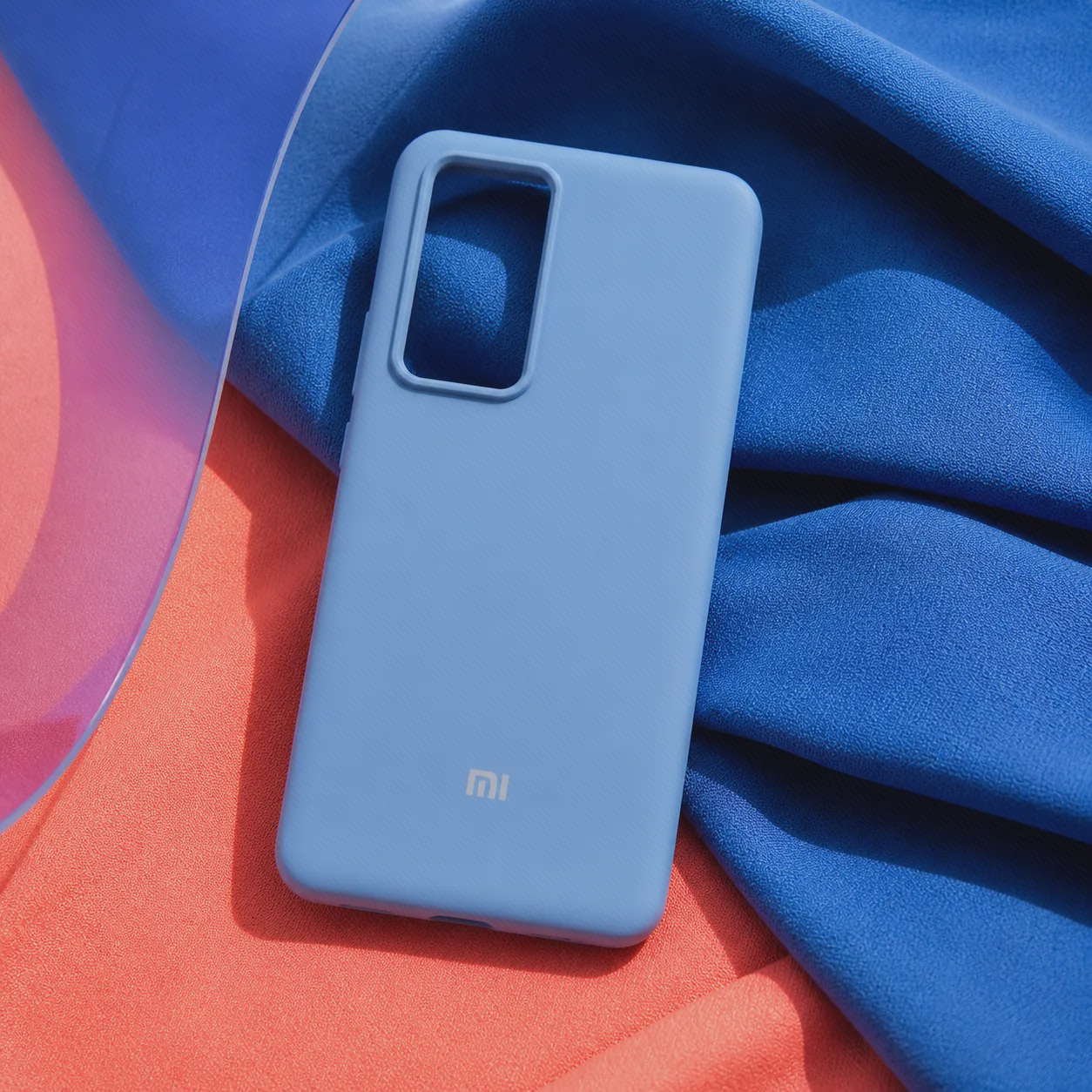 کاور سیلیکونی Xiaomi 12T در ترکیب رنگی ادیتوریال کاور سیلیکونی آبی آسمانی Xiaomi 12T روی پارچه آبی و مرجانی