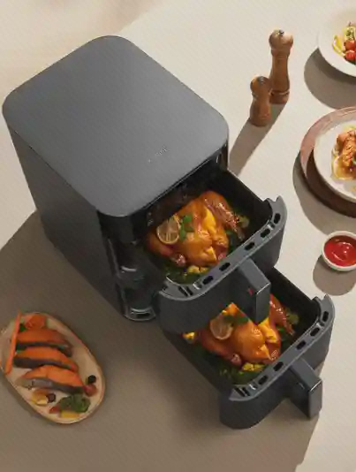 نمای بالای دو سبد هواپز Xiaomi MAF-DS1201 نمای بالای هواپز مشکی Xiaomi MAF-DS1201 با دو سبد روی هم و غذای داخل هر سبد روی میز
