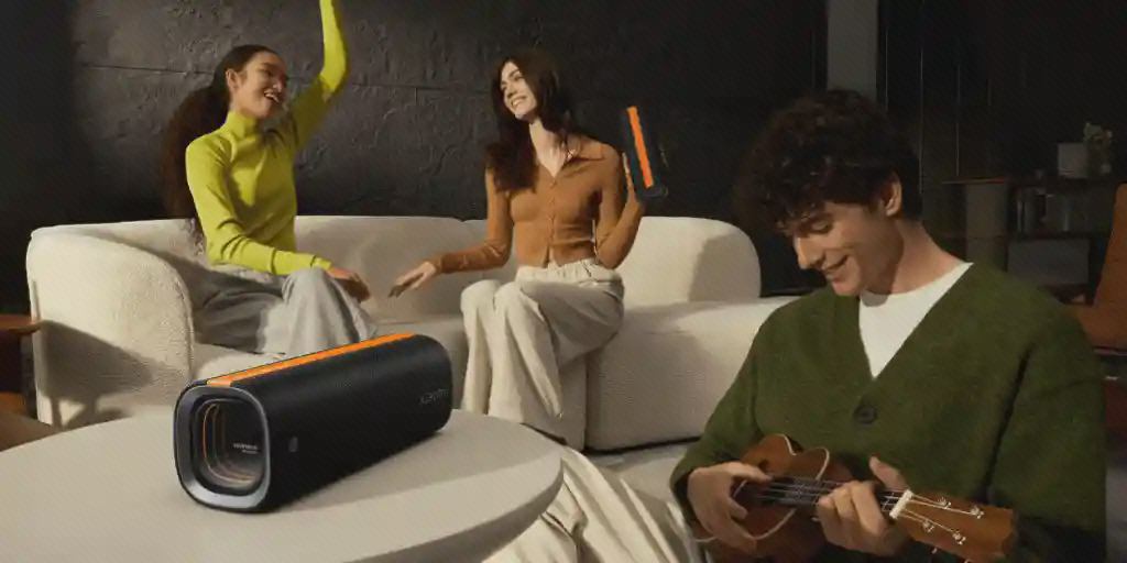 اسپیکر Xiaomi Sound Party در دورهمی خانه اسپیکر Xiaomi Sound Party روی میز مقابل مبل با سه نفر و فرد در حال نواختن ساز