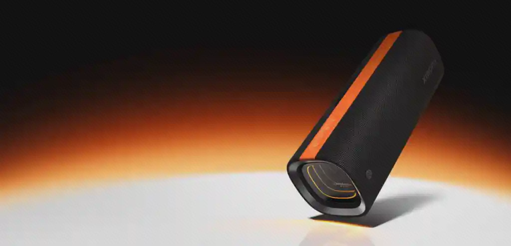 نمای زاویهدار اسپیکر Xiaomi Sound Party اسپیکر مشکی Xiaomi Sound Party MDZ-39-DB با نوار نارنجی در نمای زاویهدار روی زمینه نورانی