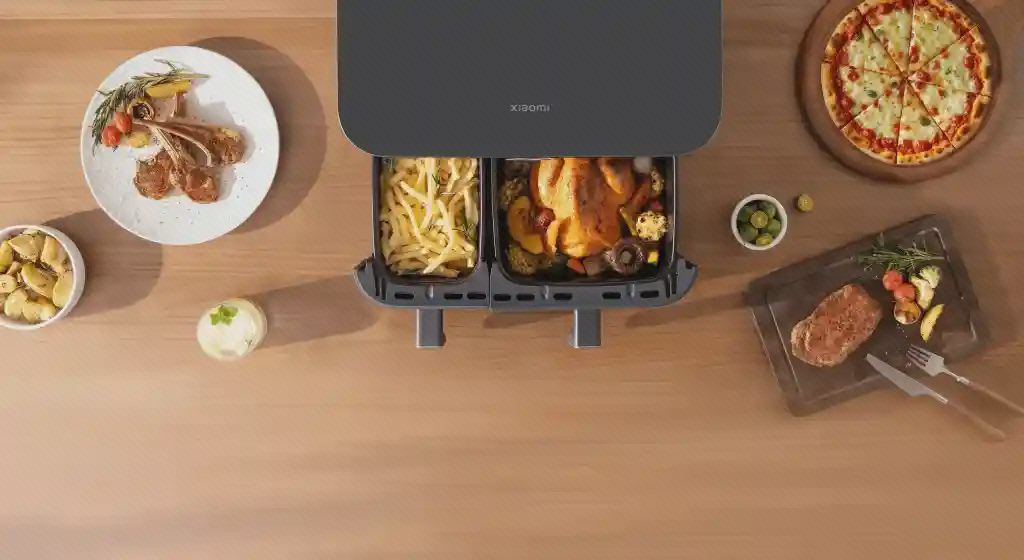 نمای بالای هواپز Xiaomi MAF-D1001 و دو سبد غذا نمای بالای هواپز Xiaomi MAF-D1001 با دو سبد باز حاوی سیبزمینی و مرغ در کنار بشقابهای غذا