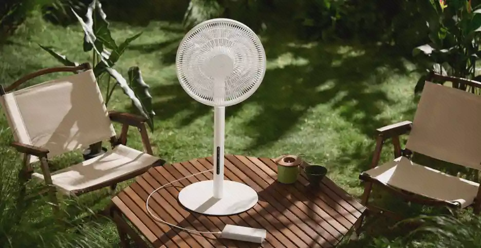 پنکه Mijia Pro Slim روی میز فضای باز پنکه Mijia Fan Pro Slim روی میز چوبی در فضای سبز میان دو صندلی
