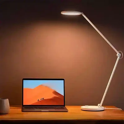نور گرم چراغ مطالعه شیائومی کنار لپتاپ چراغ Smart Desk Lamp Pro با نور گرم کنار لپتاپ روی میز چوبی