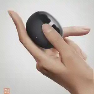 کیس گرد مشکی Mibro Buds 2 در کف دست با انگشت روی بخش بالایی آن