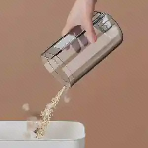 خالی کردن مخزن شفاف Deerma DX300 دست فرد مخزن شفاف Deerma DX300 را بالای سطل گرفته و زبالهها از آن خارج میشوند