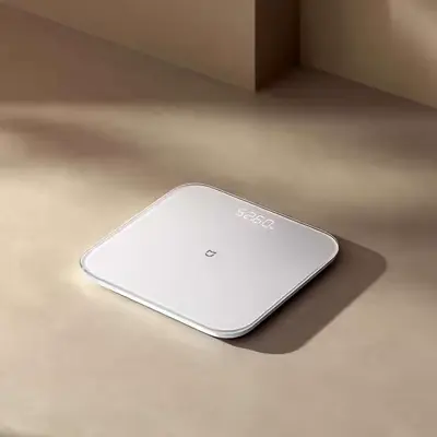 ترازوی سفید Xiaomi S200 با نمایشگر روشن روی کف زیر نور خورشید