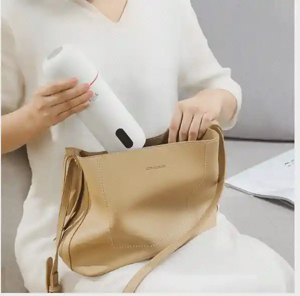فلاسک سفید DR035S در دست کنار دهانهٔ یک کیف دستی قهوه‌ای