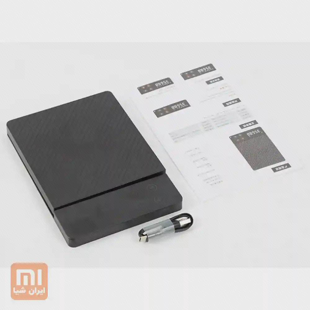 ترازوی مشکی DUKA ES1 کنار یک کابل کوتاه USB و برگهٔ راهنما