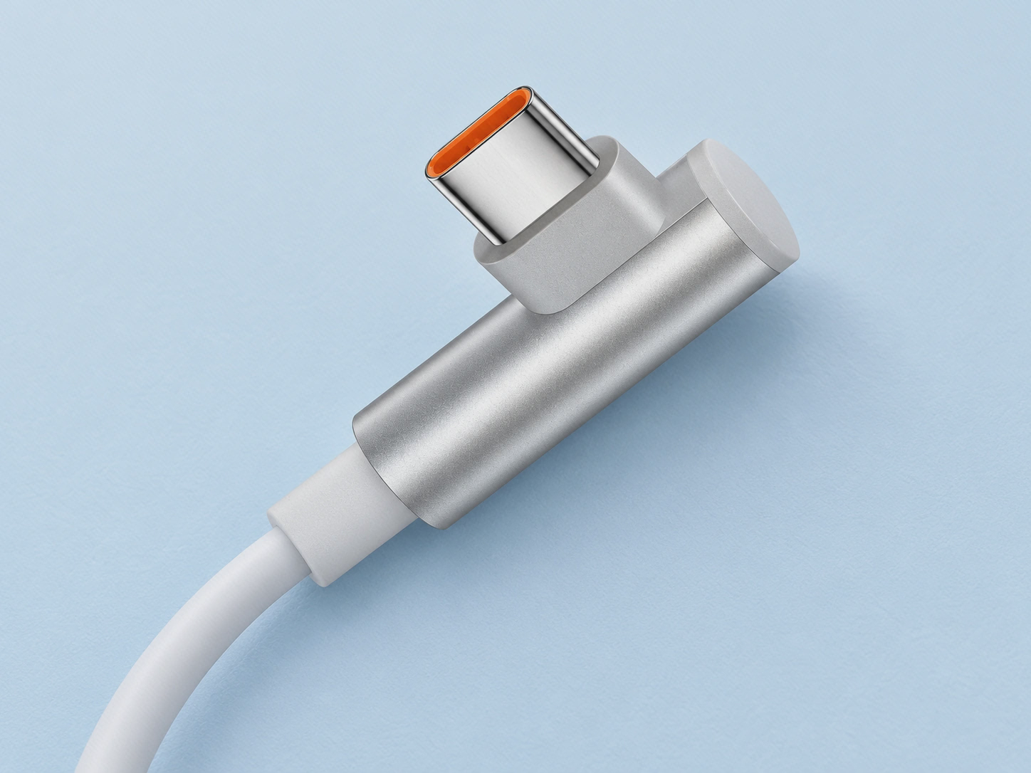 نمای بازسازی‌شدهٔ فیش USB-C زاویه‌دار نقره‌ای‌رنگ با بخش نارنجی داخل سوکت و سیم سفید روی سطح آبی روشن