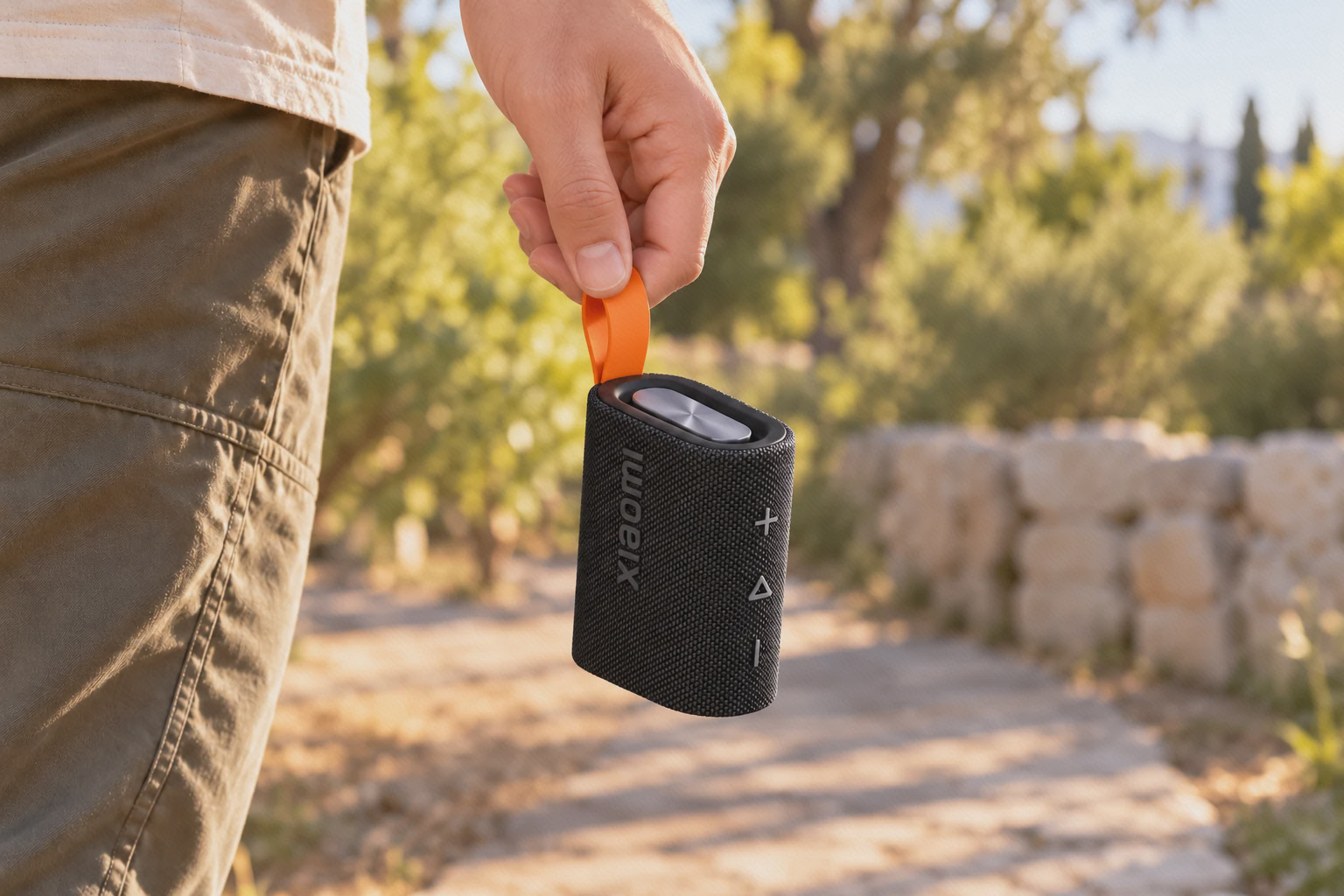اسپیکر مشکی Sound Pocket شیائومی با بند نارنجی در دست، بیرون از خانه
