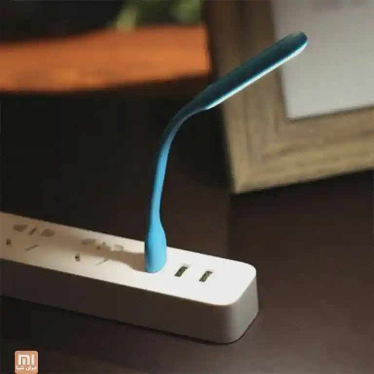 تغذیهٔ چراغ Light Plus از درگاه USB چراغ آبی خمشوندهٔ شیائومی روشن و متصل به درگاه USB یک چندراهی سفید