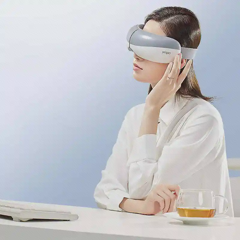 استفادهٔ نشسته از ماسک EYE5 کاربر نشسته پشت میز با ماسک سفید و خاکستری Pangao EYE5 روی چشمها