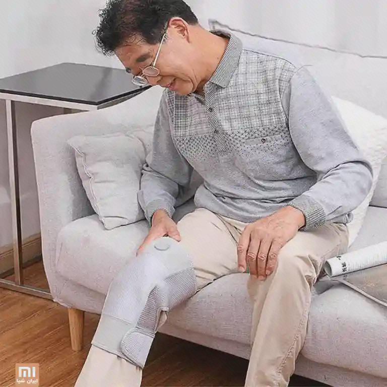 زانوبند G10 هنگام استراحت مرد نشسته روی مبل با زانوبند خاکستری PMA-G10 دور زانو