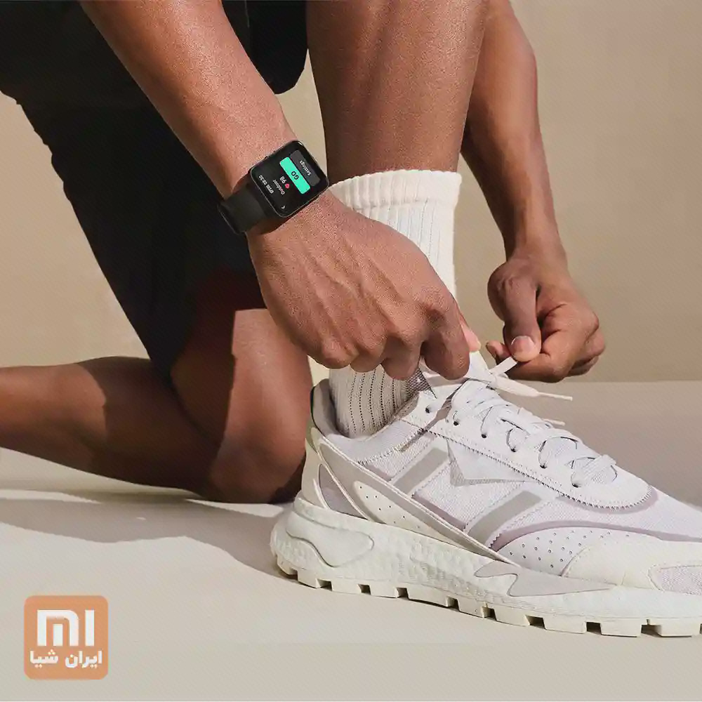 Redmi Watch 2 Lite هنگام آمادهشدن برای ورزش Redmi Watch 2 Lite مشکی روی مچ فردی که بند کفش ورزشی را میبندد