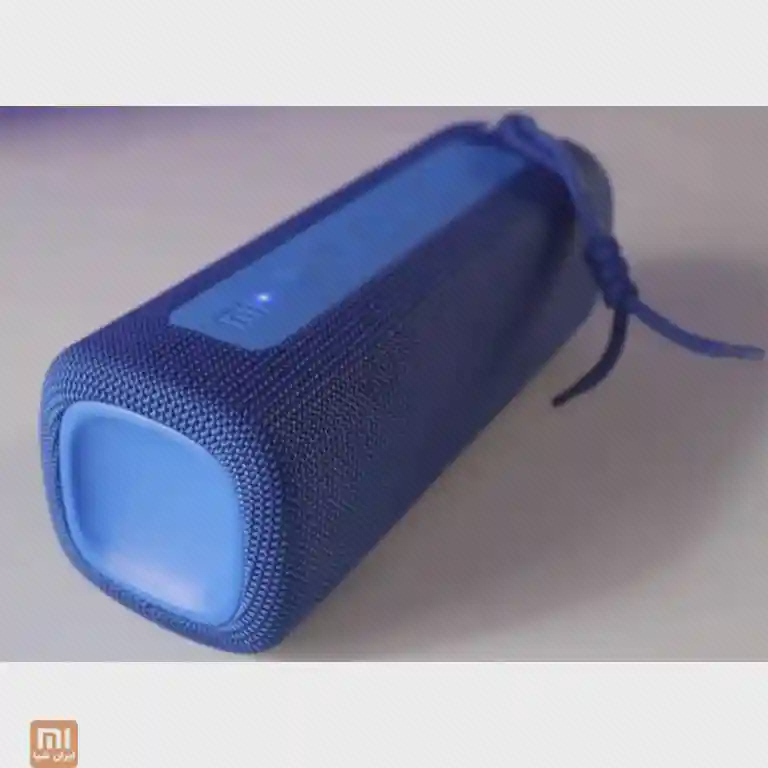 اسپیکر آبی MDZ-36-DB به حالت خوابیده روی سطح روشن با بند و چراغ روشن کنار کلیدها